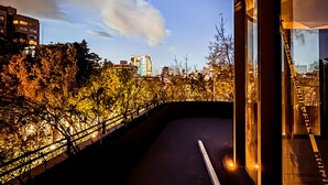 A modern building with large windows, a balcony, and a view of a cityscape with trees and buildings. - EMA Condesa (Mexico City)