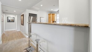Eine moderne Küche mit einem Edelstahlkühlschrank, Holzschränken und einer Arbeitsplatte aus Granit.