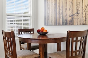 A round wooden dining table with a bowl of fruit, surrounded by four wooden chairs with woven seat cushions. - Main Floor 2BR Retreat, 2 Parking, 1 Bath & Wi-Fi (Pickering)