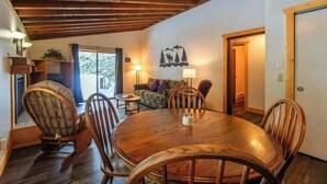 Un espace repas comprenant une table et des chaises en bois, un canapé et un élément décoratif fixé au mur.