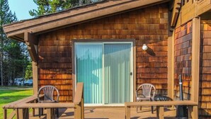 Une cabane en bois avec une terrasse, deux chaises et une porte-fenêtre coulissante.