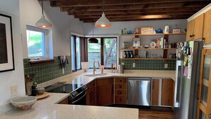 A kitchen with a stainless steel dishwasher, wooden cabinets, a window, and a countertop with a bowl. - A conscious retreat overlooking the Delaware River (Beach Lake)