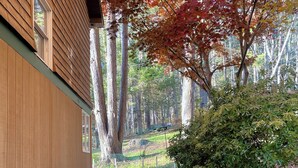 A wooden building with a stone pathway leading to a gate, surrounded by trees and a small bush. - A conscious retreat overlooking the Delaware River (Beach Lake)