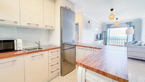 Una cocina moderna con microondas integrado, un refrigerador y una encimera de madera.