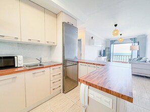 A modern kitchen with a built-in microwave, a refrigerator, and a wooden countertop. - Apartment with breathtaking view (Porís de Abona)
