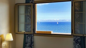 Una habitación con ventana que ofrece vista al mar y un velero.
