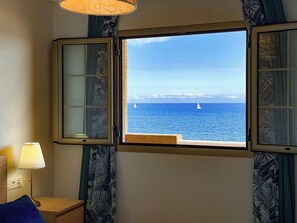 A room with a window offering a view of the sea and a sailboat. - Apartment with breathtaking view (Porís de Abona)