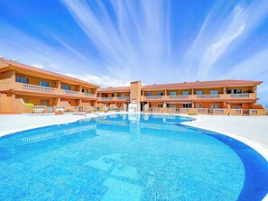 A hotel with a large swimming pool, multiple balconies, and a clear blue sky. - Apartment with breathtaking view (Porís de Abona)