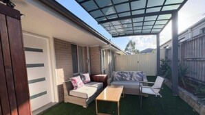 A covered patio with a sofa, chairs, and a table.