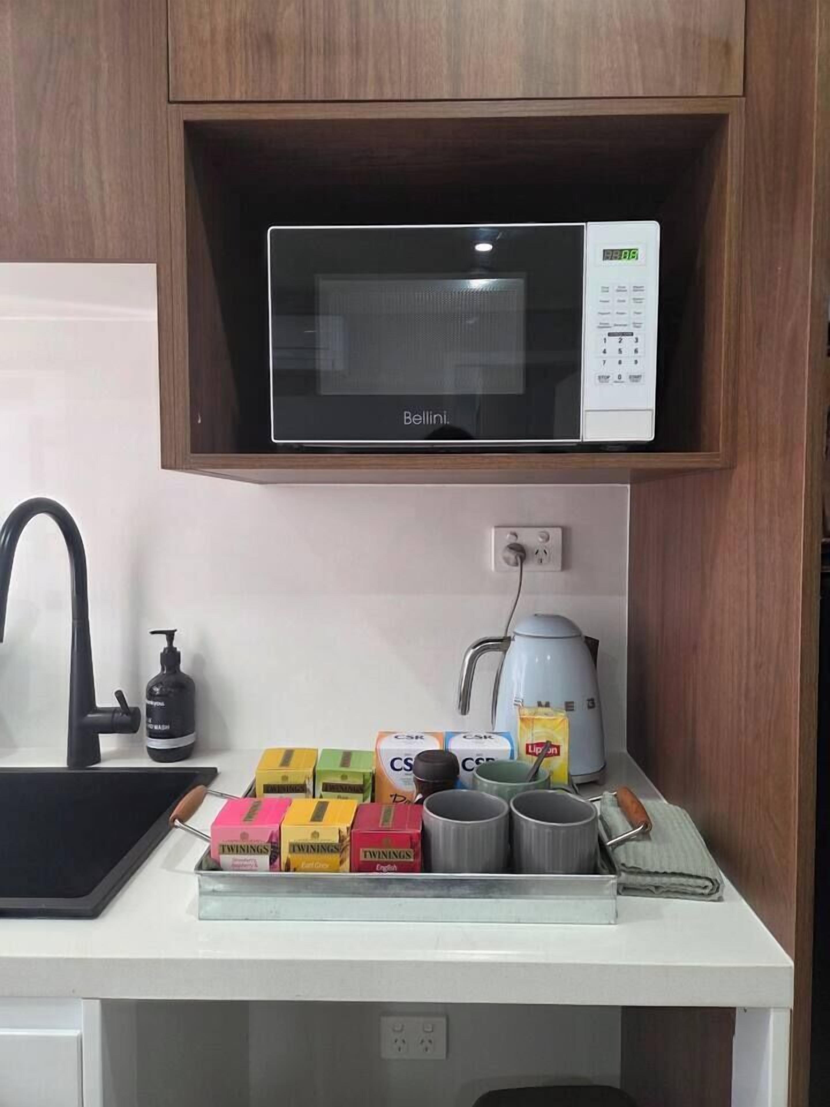 A kitchen with a microwave, a kettle, and a sink.