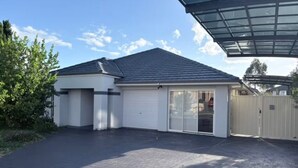 A modern house with a garage, a covered patio, and a fenced backyard.