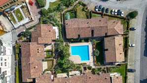 An aerial view of a residential area with multiple houses, a central swimming pool, and a parking area. - MGH- Garda Hills Family Stay (Polpenazze del Garda)