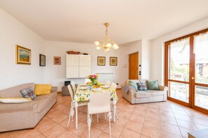 Ein Wohnzimmer mit Esstisch, zwei Sofas, einer Chandelier und einem großen Fenster.