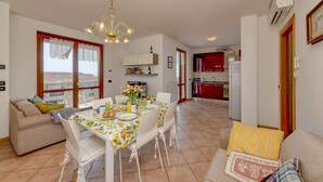 A compact living space with a dining area, kitchenette, and a sofa. - MGH- Garda Hills Family Stay (Polpenazze del Garda)