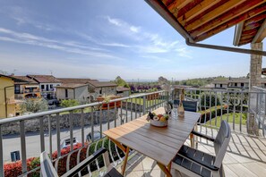 Ein Balkon mit Holztisch, Stühlen und einer Obstschale.