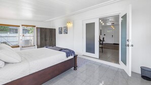 A bedroom with a bed, a door leading to a balcony, and a view of the outside. - Relaxing Stay Minutes from the beach (Seminole)