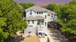 A two-story house with a front porch, a covered patio, and a basketball hoop. - 5BR Outer Banks Retreat ✦ Pool ✦ Spa ✦ Private Beach Access Prkg ✦ Dog-Friendly (Southern Shores)