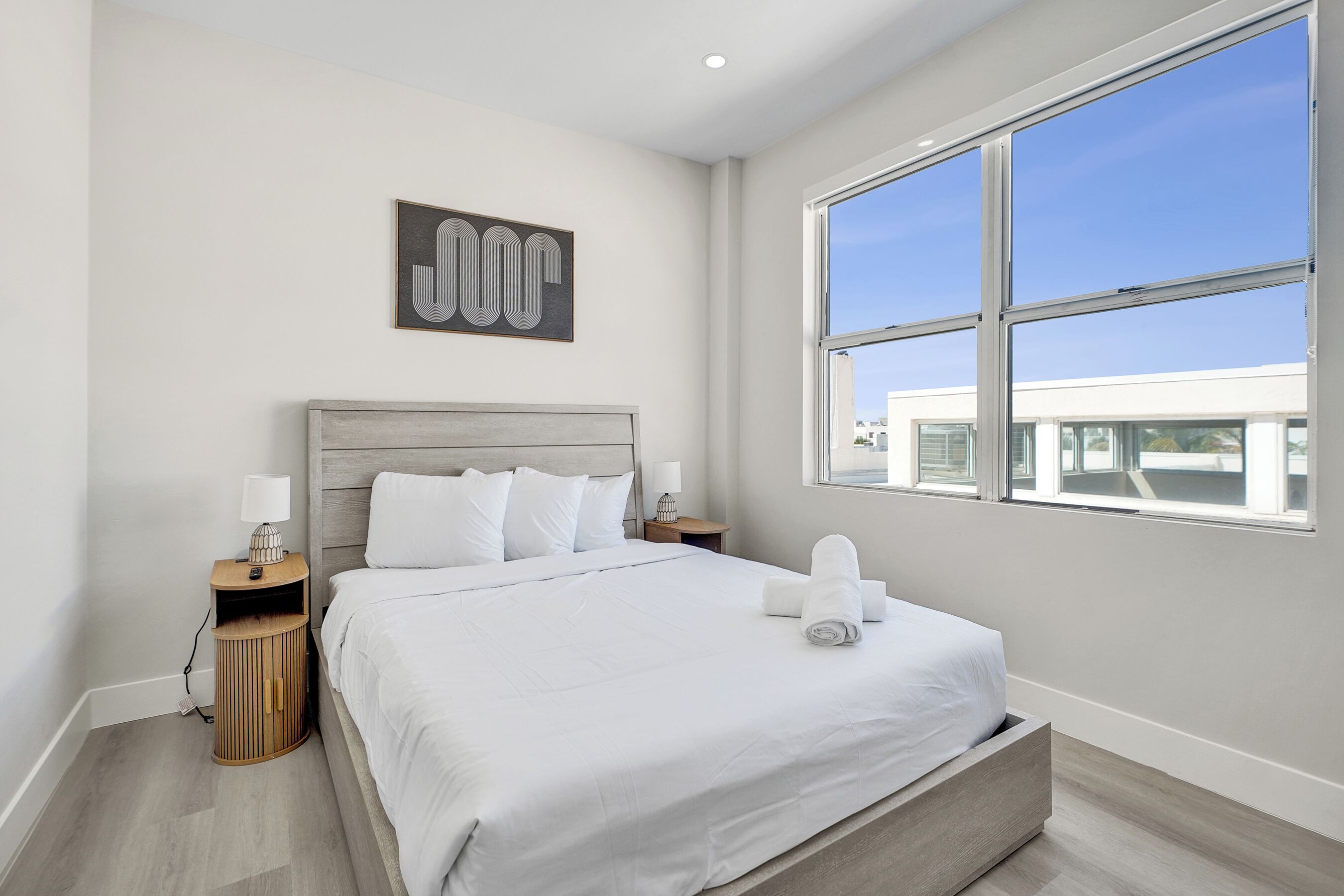 Une chambre d’hôtel moderne dotée d’un grand lit, d’une table de chevet, d’une commode, d’une fenêtre et offrant une vue sur la ville.