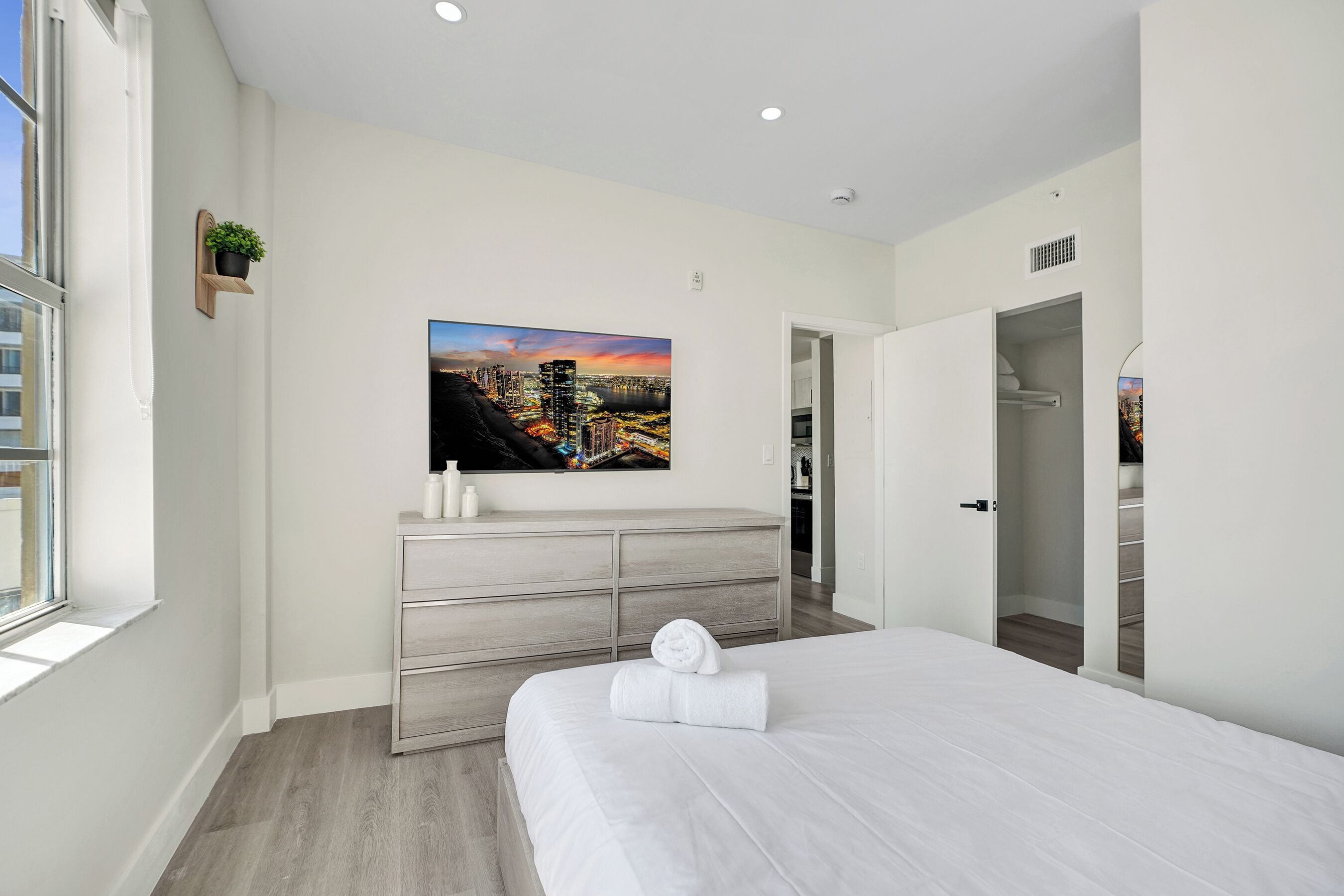 Een moderne slaapkamer met een groot bed, een dressoir, een schilderij en een kast.