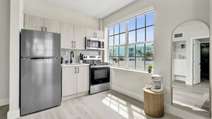 A modern kitchen with stainless steel appliances, a large window, and a view of the outside. - SoBe Suites 727 (Miami Beach)