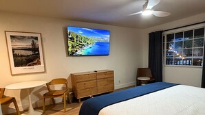Habitación de hotel con cama, escritorio, silla, cómoda, televisor y ventana con vista al exterior.
