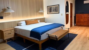 Un dormitorio moderno con una cama de madera, un banco, una mesita de noche y un armario.