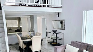 A spacious living area with a balcony, a dining area, and a sofa. - Luxury Apartment in Waikiki E5 Close to the Beach (Ballito)