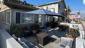 A residential backyard with a patio area, outdoor furniture, and a large umbrella. - 3bed 2bath beach cottage Steps to the Sand in MB (San Diego)