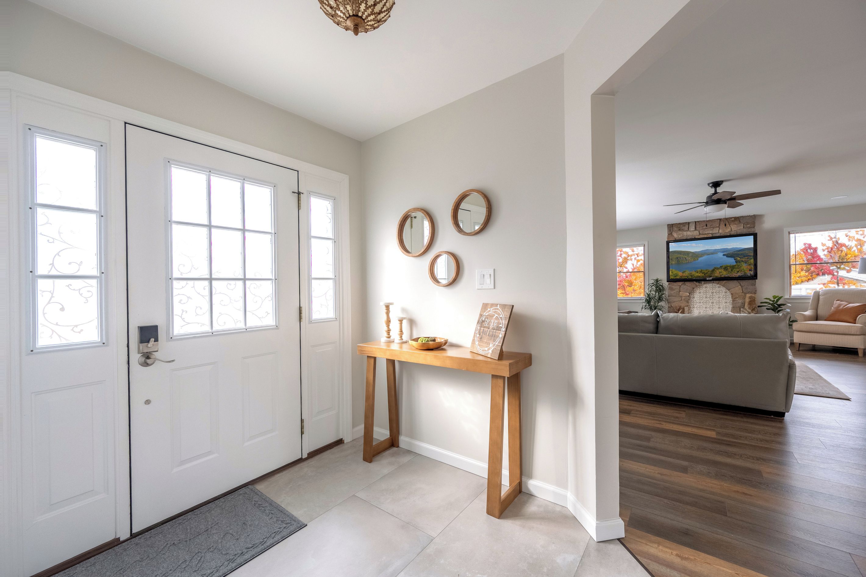 A modern interior with a white door, a wooden console table, and a stone fireplace.