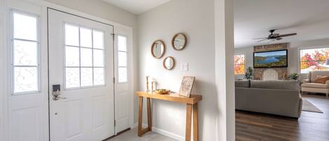 A modern interior with a white door, a wooden console table, and a stone fireplace.