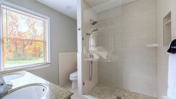 A modern bathroom with a shower, toilet, and sink.