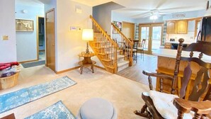 A spacious living area with a staircase, a dining table, and a kitchen in the background. - Spacious A-Frame Family Beach Getaway - Sleeps 8 (Ocean Pines)