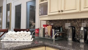 A kitchen with a marble countertop, a coffee maker, a kettle, and a roll of paper towels. - Richmond Hill Mansion | Ultimate Executive Retreat (Richmond Hill)