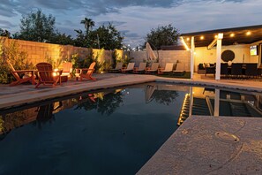Une piscine avec des chaises longues et un espace de détente abrité.
