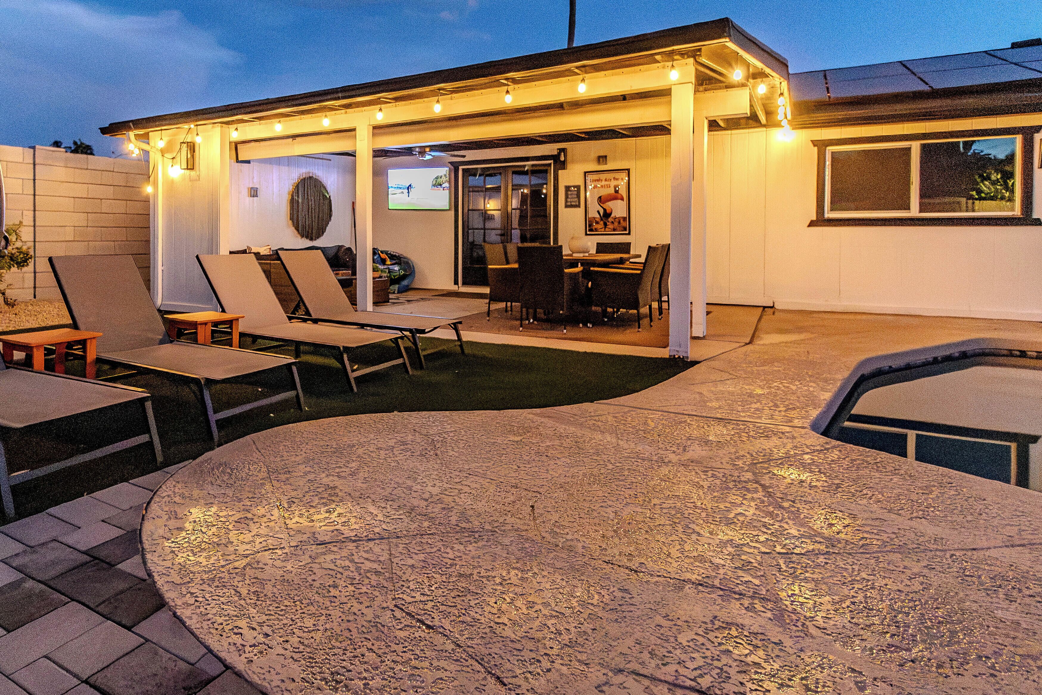 Un espace extérieur aménagé en patio, avec un coin salon couvert, une table à manger et un barbecue.