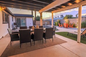 Une terrasse extérieure avec une table et des chaises pour les repas, un barbecue et une piscine.