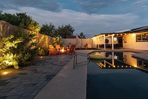 A pool area with lounge chairs and a small table, surrounded by a brick wall and vegetation. - Great 4BR Pool Home – Perfect for Families & Group Getaways (Phoenix)