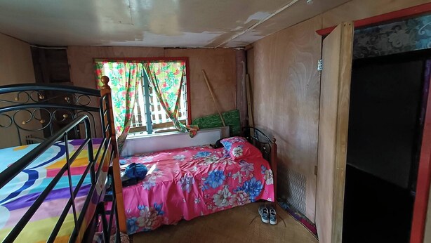 Ein Schlafzimmer mit Etagenbett, einem Einzelbett, einem Fenster mit Vorhängen, einer Tür und einem kleinen Teppich.