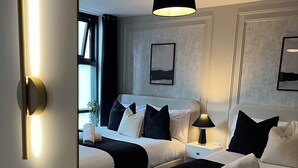 A hotel room with two beds, a bedside table, a lamp, a ceiling light, and a mirror. - Liverpool City Centre Luxury 2 Bedroom 2 Bathroom Balcony Flat - Cheap Parking (Liverpool)