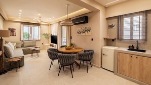 Un espacio habitable moderno con sofá, mesa de comedor, sillas, una pequeña cocina y televisor.