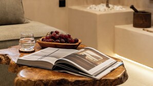 Un salón acogedor con un sofá, una mesita de centro con un frutero, un vaso de agua y una revista.