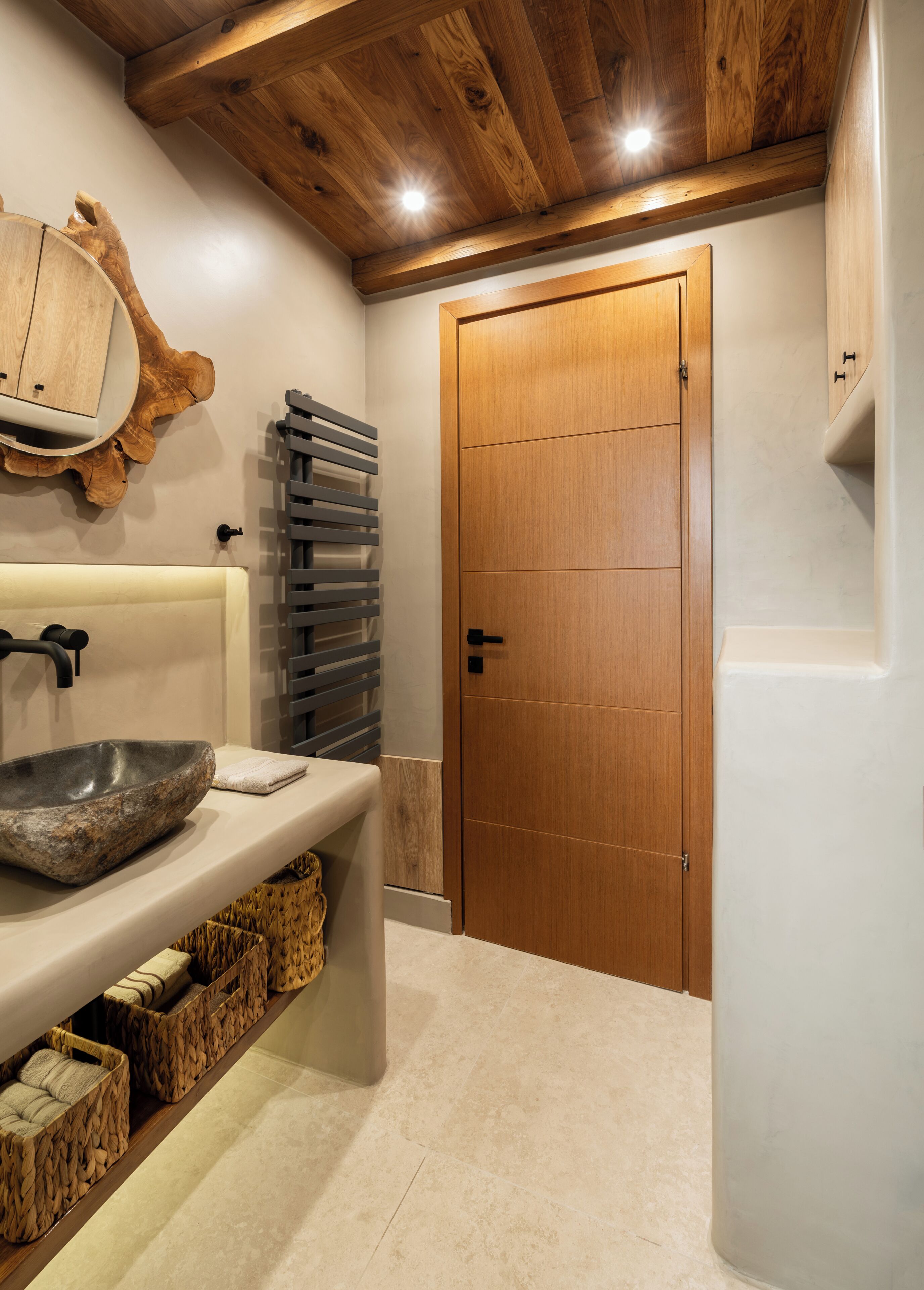 A bathroom with a stone basin, wooden cabinets, a wooden ceiling, and a tiled floor.