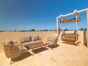 An outdoor seating area with a sofa, chairs, a table, and a swing. - Hotel Kaan Holbox (Isla Holbox)