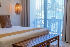 Un dormitorio con cama, un banco de madera, una lámpara colgante y vistas al exterior a través de un ventanal grande.