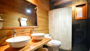 Puisesta materiaalista tehty kylpyhuone, jossa on kaksi pesuallasta, wc ja peili.