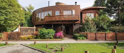 A modern building with a circular design, a signboard, and a well-maintained garden with a gravel path.