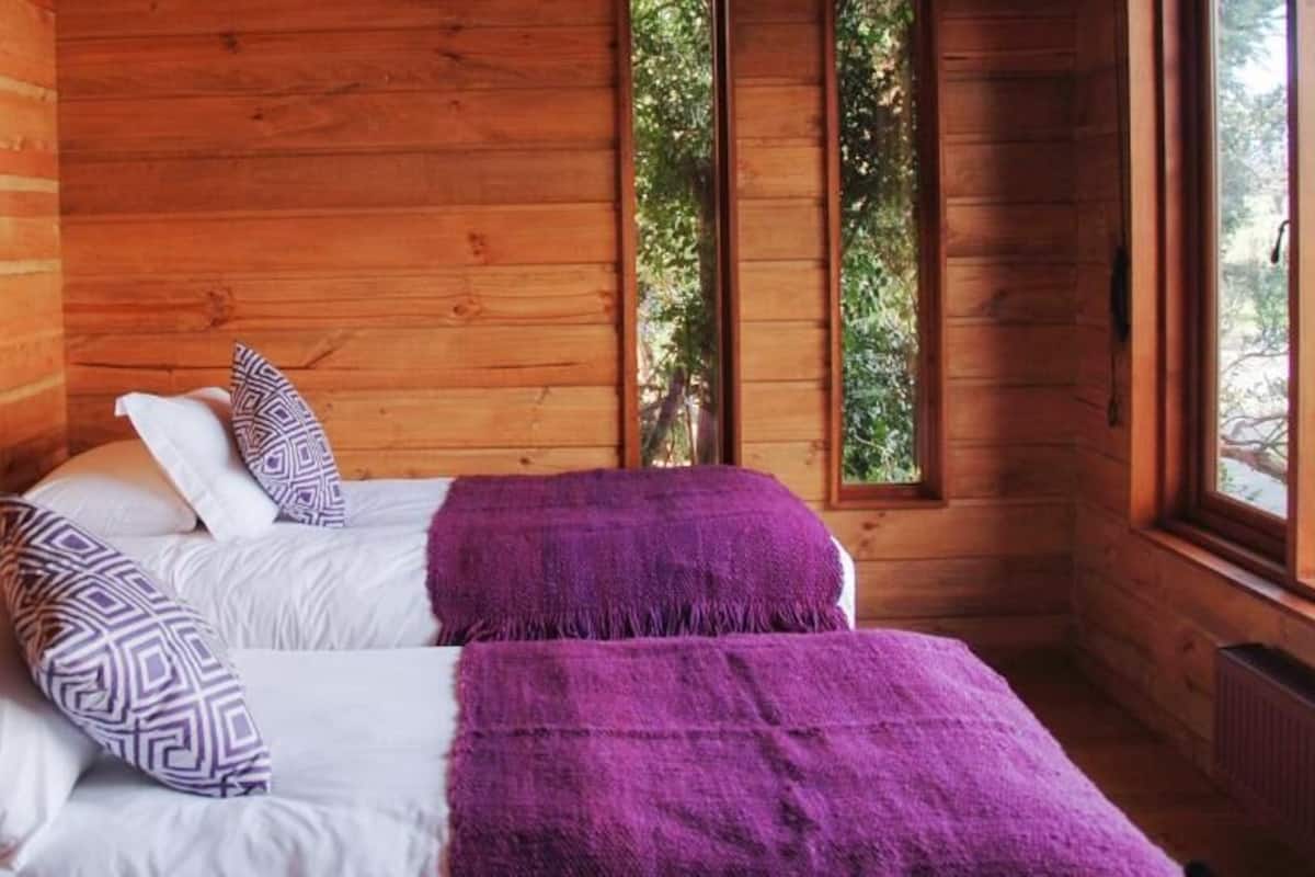 Habitación de cabaña de madera con cama, almohadas y ventana.