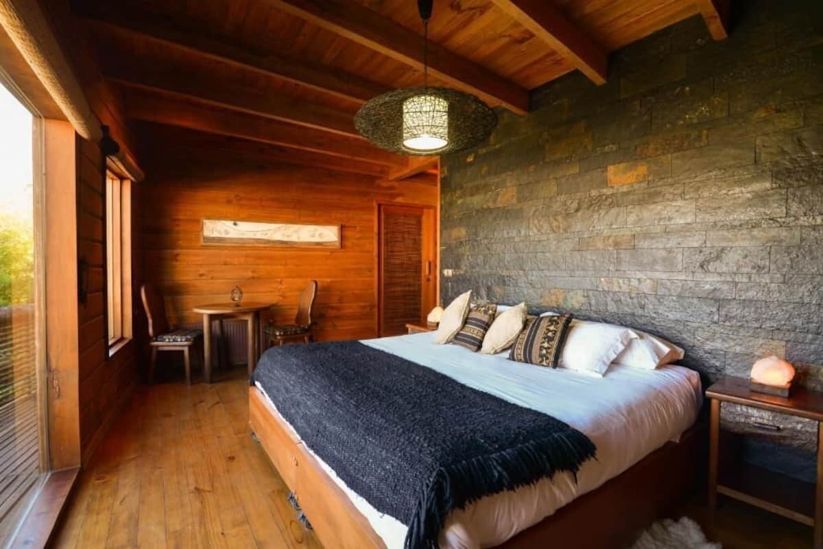 Un dormitorio de cabaña de madera con cama, una mesa y una silla.