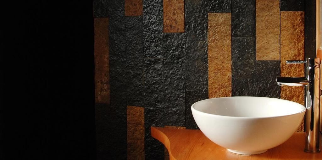 A white bowl sink with a modern faucet in a bathroom with a textured wall.