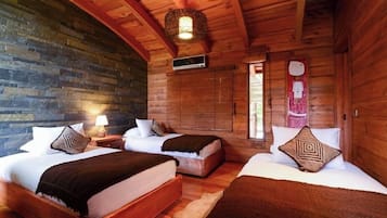 Une cabane en bois avec deux lits, un mur en pierre et un luminaire suspendu.
